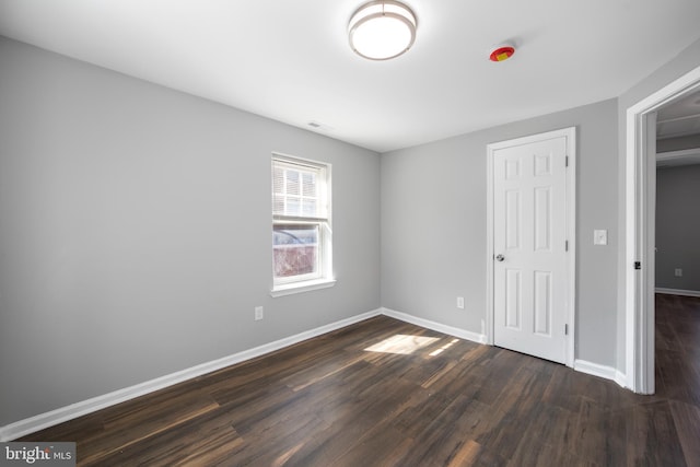 unfurnished bedroom with dark wood finished floors, visible vents, and baseboards