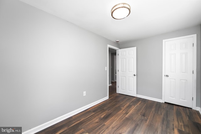 unfurnished bedroom featuring baseboards and dark wood-type flooring