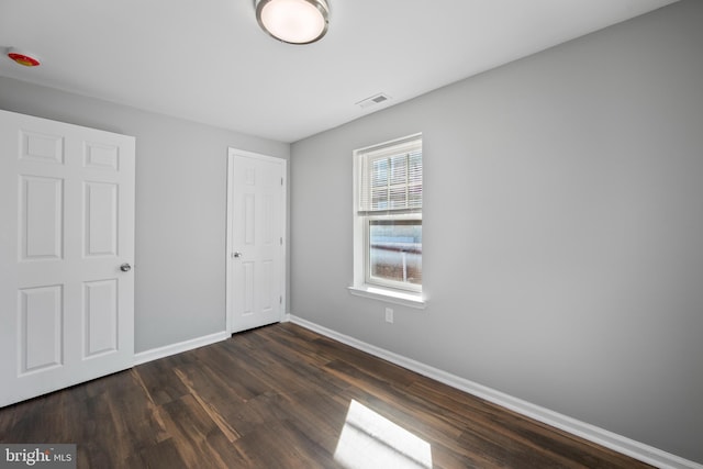 unfurnished bedroom featuring baseboards, visible vents, and dark wood finished floors