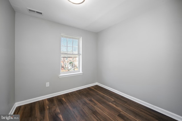 unfurnished room with dark wood-style floors, visible vents, and baseboards