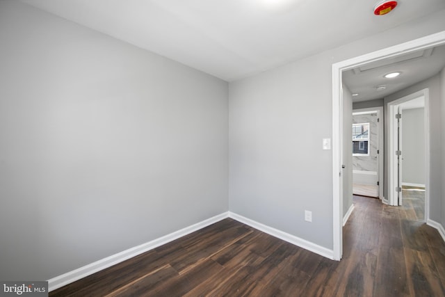 spare room with dark wood-style flooring and baseboards