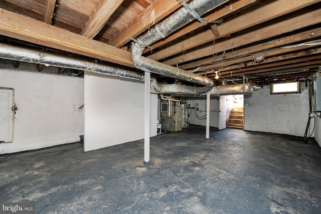 basement featuring stairway, electric panel, and heating unit