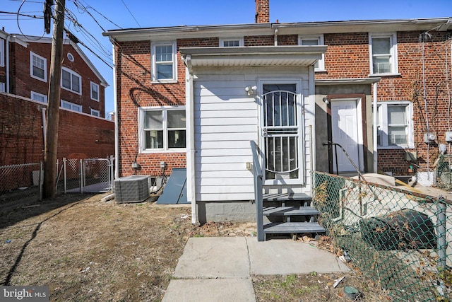 multi unit property featuring central air condition unit, a gate, fence, and brick siding