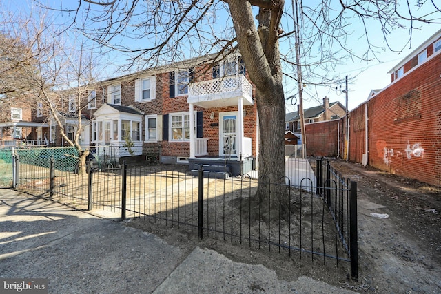 townhome / multi-family property with brick siding, a fenced front yard, a residential view, and a balcony