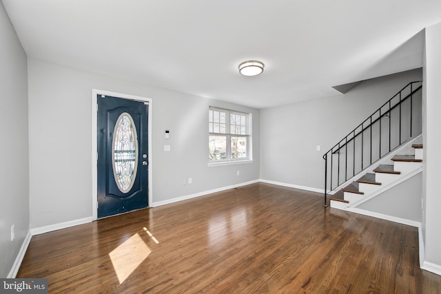 foyer entrance featuring baseboards, stairway, and wood finished floors