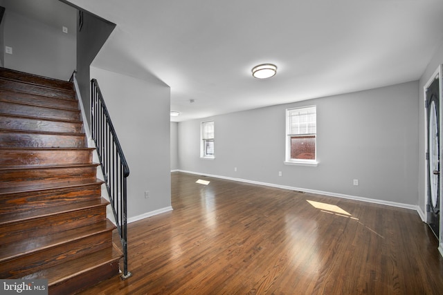 interior space featuring dark wood-style flooring, stairway, and baseboards