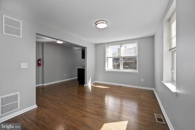 unfurnished living room featuring baseboards, visible vents, and wood finished floors