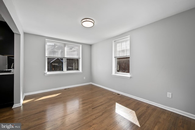 empty room featuring visible vents, baseboards, and wood finished floors