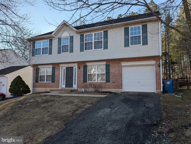 colonial house with a garage, brick siding, and driveway