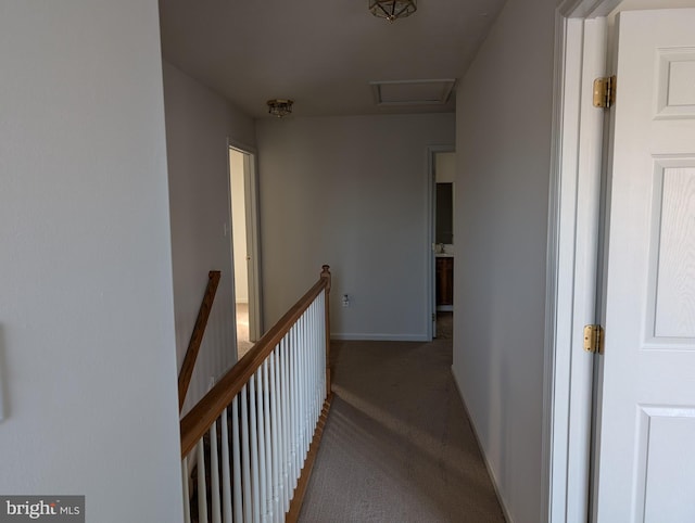 hallway with an upstairs landing, baseboards, attic access, and carpet