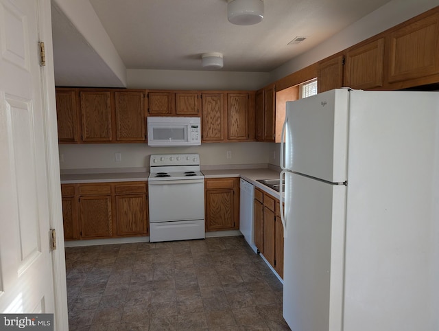 kitchen featuring white appliances, visible vents, light countertops, stone finish floor, and brown cabinets