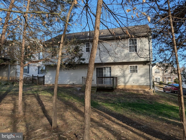 rear view of house featuring fence, a lawn, and a wooden deck