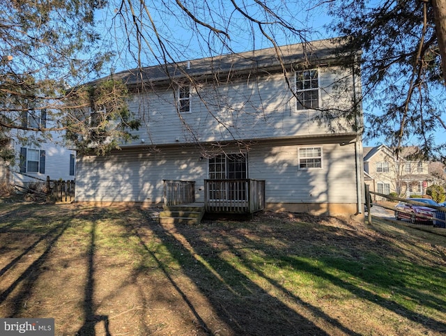 rear view of house featuring a lawn, a wooden deck, and fence