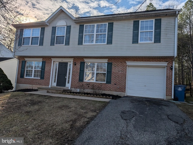 colonial home featuring aphalt driveway, brick siding, and a garage