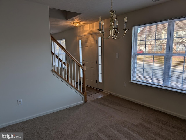 carpeted entryway featuring a notable chandelier, stairs, and baseboards