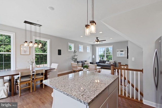 kitchen featuring light stone counters, decorative light fixtures, recessed lighting, light wood-style floors, and freestanding refrigerator