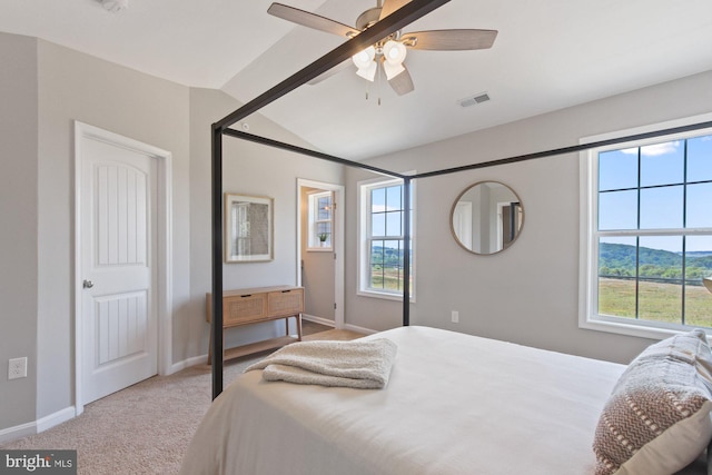 bedroom featuring vaulted ceiling, multiple windows, visible vents, and light colored carpet