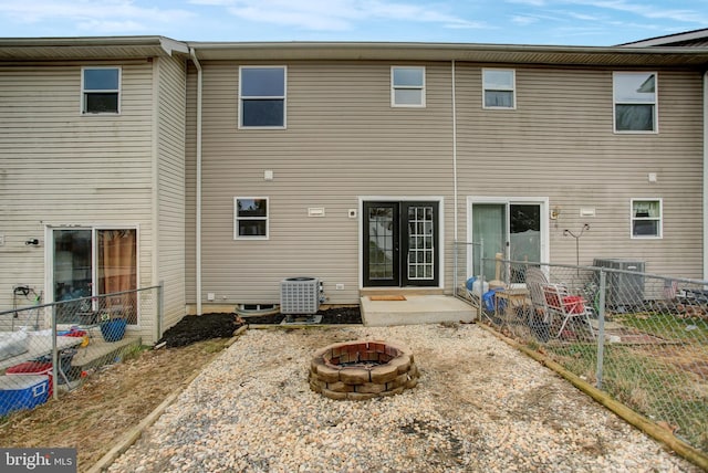 rear view of house with french doors, an outdoor fire pit, fence, and central air condition unit