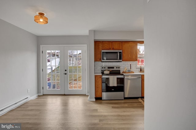 kitchen with french doors, appliances with stainless steel finishes, light wood-type flooring, and tasteful backsplash