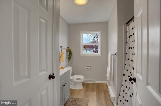 full bathroom featuring toilet, wood finished floors, visible vents, vanity, and baseboard heating