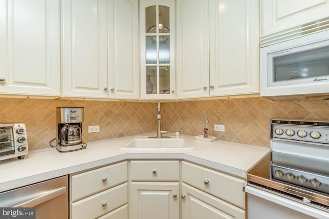 kitchen with electric range oven, white microwave, backsplash, stainless steel dishwasher, and a sink