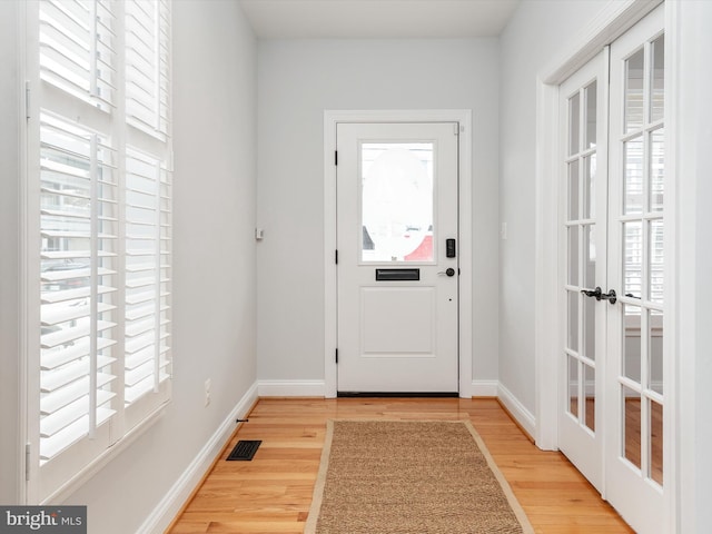 entryway featuring light wood finished floors, baseboards, and french doors