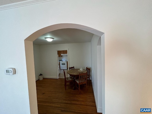 dining room with arched walkways, wood finished floors, and baseboards