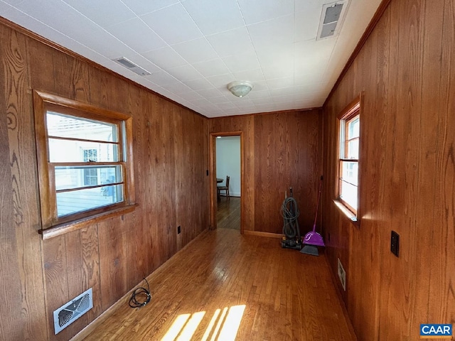 empty room with wood-type flooring, wooden walls, and visible vents