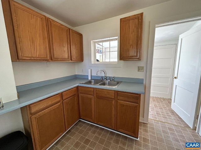 kitchen featuring light countertops, a sink, and brown cabinets