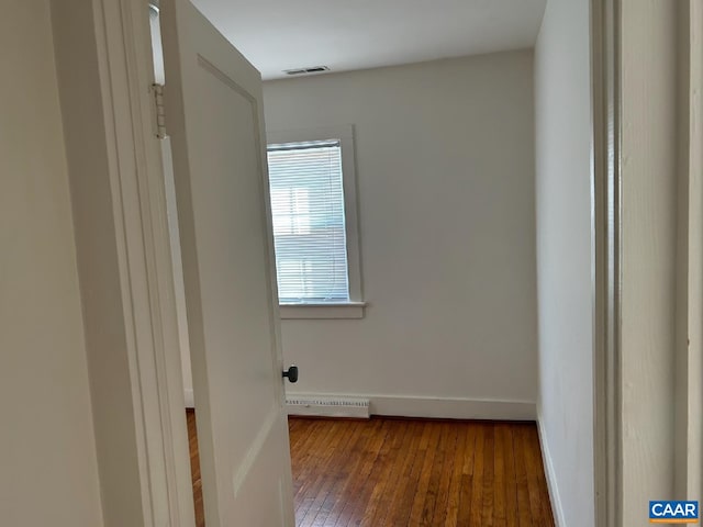 spare room featuring wood-type flooring, visible vents, and baseboards