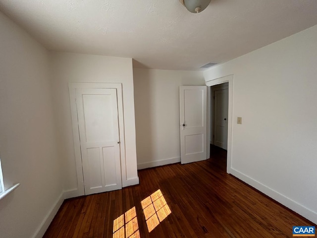 unfurnished bedroom with wood-type flooring, visible vents, and baseboards