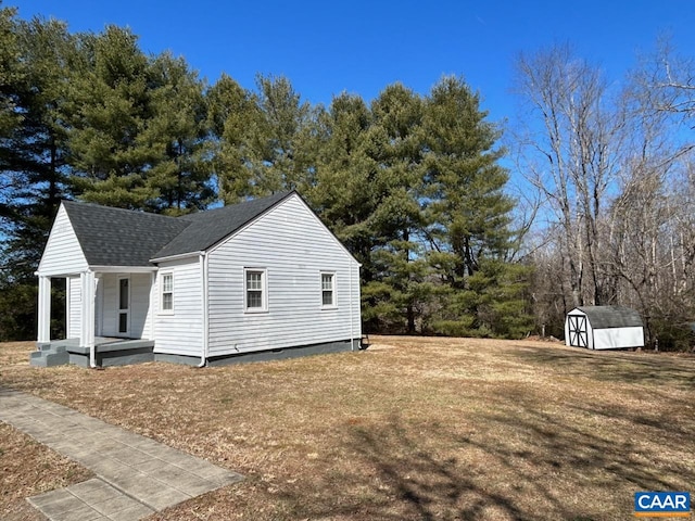 view of side of home with a storage shed, a yard, a shingled roof, and an outdoor structure