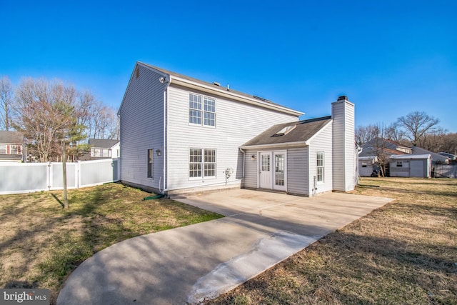 back of property featuring a patio area, fence, a chimney, and a lawn