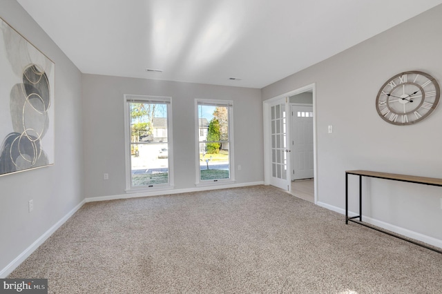 carpeted spare room featuring visible vents and baseboards