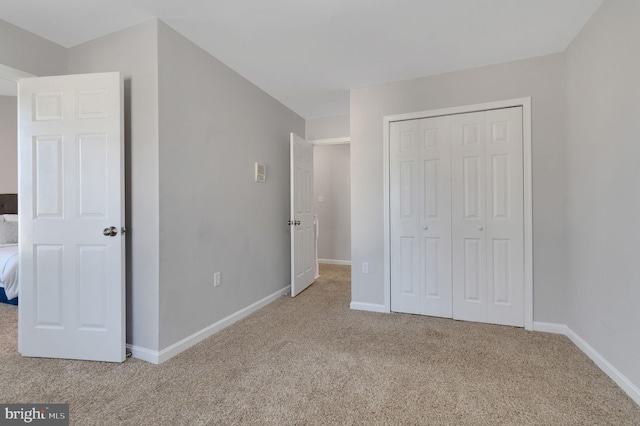 unfurnished bedroom with a closet, carpet, and baseboards