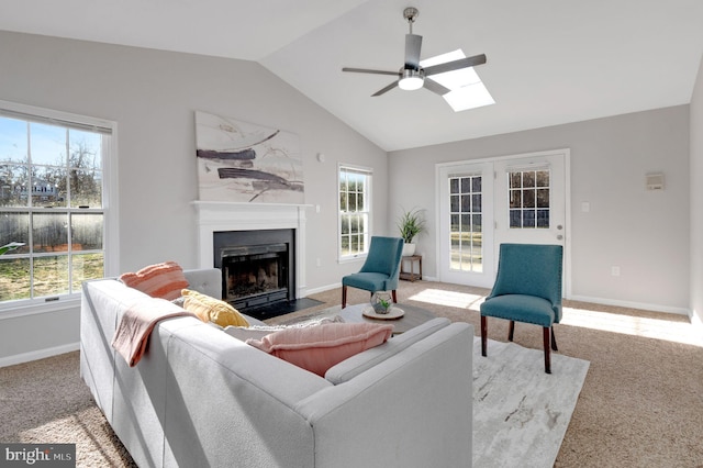 living area featuring vaulted ceiling with skylight, carpet, a fireplace with flush hearth, and a healthy amount of sunlight