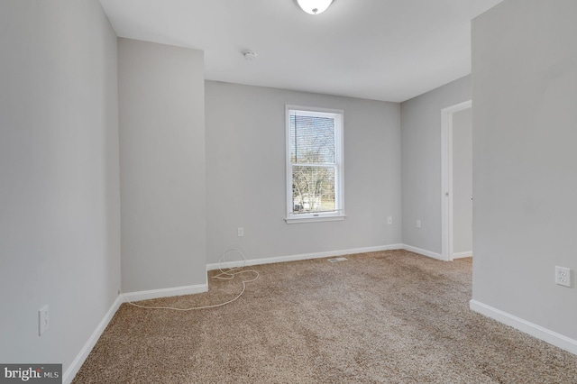 spare room with carpet floors, visible vents, and baseboards