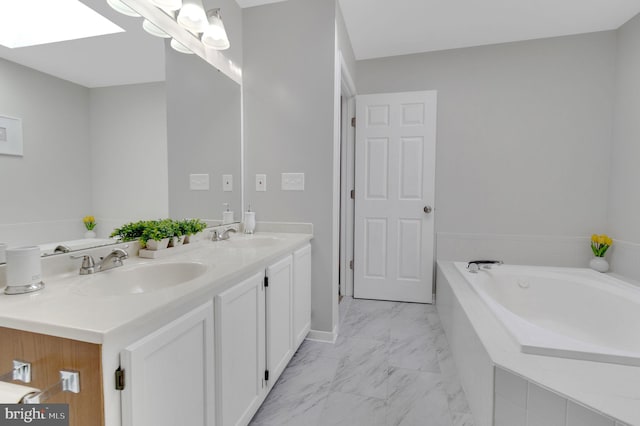 full bath featuring marble finish floor, a skylight, a sink, and a bath