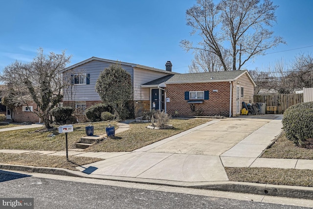 split level home with a wall unit AC, a chimney, fence, and brick siding