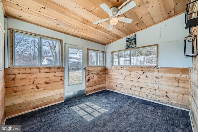 interior space featuring lofted ceiling, wooden ceiling, wooden walls, and a ceiling fan