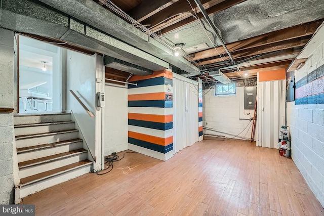 basement featuring electric panel, stairway, and wood finished floors