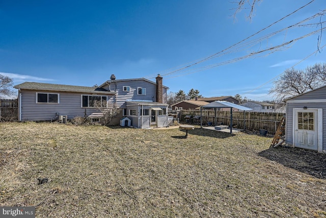 rear view of house featuring a yard, a chimney, fence private yard, and central air condition unit