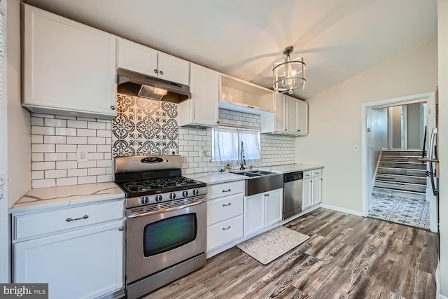 kitchen featuring lofted ceiling, under cabinet range hood, stainless steel appliances, a sink, and dark wood-style floors