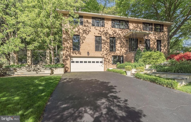 view of front of house with brick siding, a front yard, aphalt driveway, and a garage