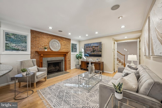 living room featuring light wood-style flooring, a fireplace, crown molding, and baseboards