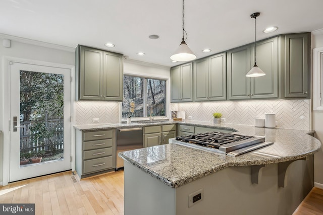 kitchen with light stone counters, a peninsula, light wood-style flooring, appliances with stainless steel finishes, and decorative light fixtures