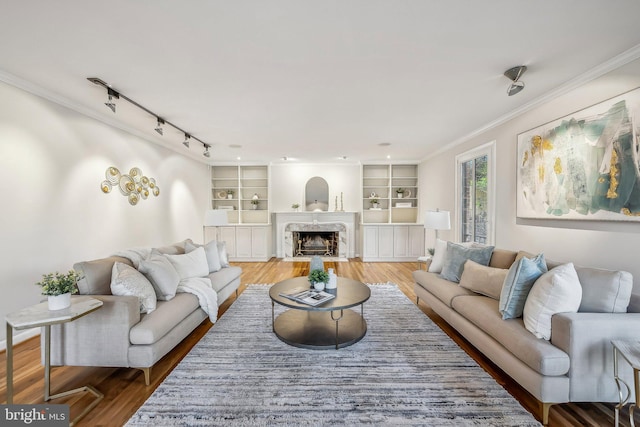 living room featuring wood finished floors, a high end fireplace, and ornamental molding