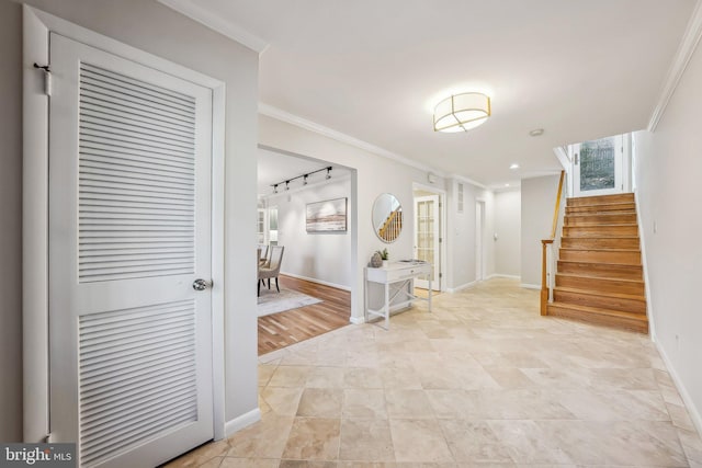 foyer entrance with stairs, track lighting, baseboards, and ornamental molding