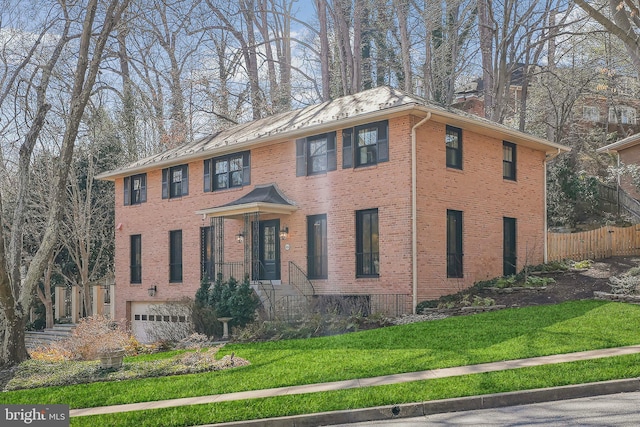 colonial-style house featuring brick siding, a chimney, a front lawn, and fence