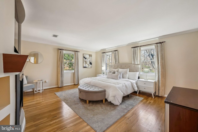 bedroom featuring visible vents, multiple windows, and light wood-style flooring